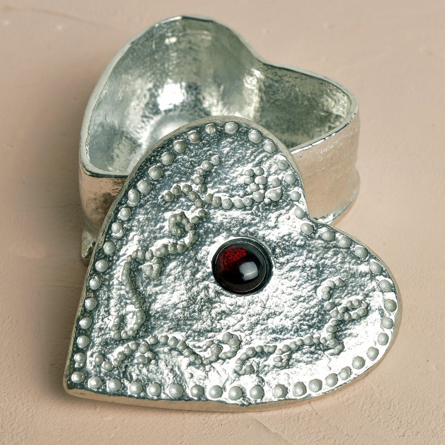 A personalised heart shaped pewter keepsake box with a garnet stone in the middle. The underside of the lid can be engraved with your personalised message. A perfect 10th (Tin) ten year wedding anniversary gift (Our pewter is 95% tin).