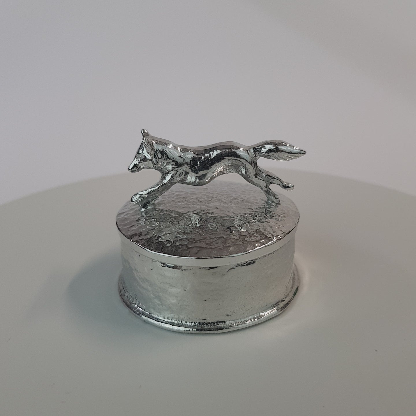 Video of a pewter trinket box with a fox sculpture on the lid. The underside of the lid can be engraved. Made by  Glover and Smith handmade pewter UK.