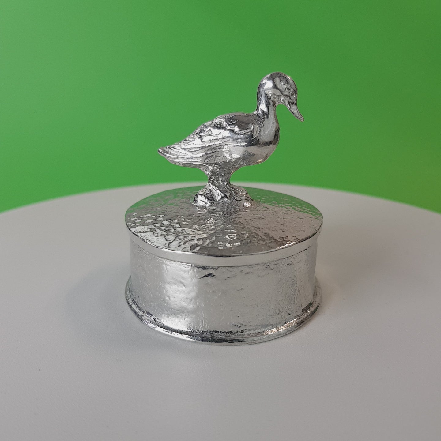 Video of a pewter trinket box with a duck sculpture on the lid. The underside of the lid can be engraved. Made by  Glover and Smith handmade pewter UK.