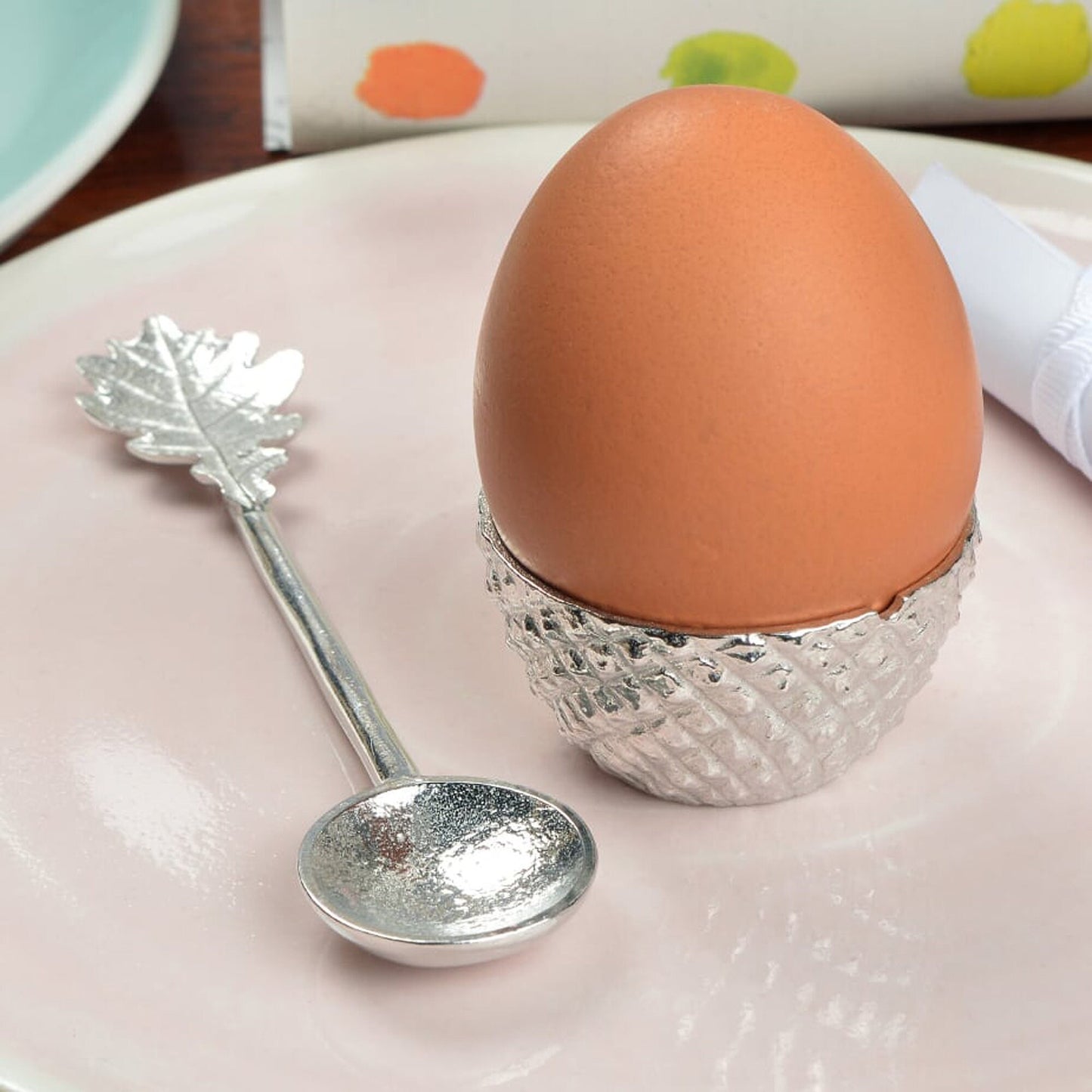 Our pewter 'Acorn Cup' egg cup features the lovely natural texture and pattern of an acorn cup and when an egg is placed in it, has the appearance of an acorn. With an oak leaf topped spoon. Christening gifts for boys and girls.