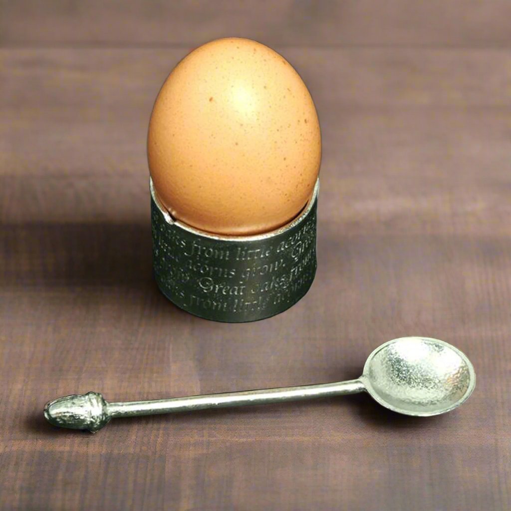 A circular egg cup with the proverb 'Great oaks from little acorns grow' written around the outside with an acorn finialled spoon. We engrave your message on the inside. Christening gifts for boys and girls.