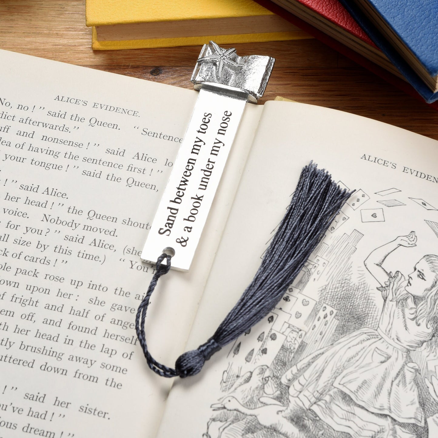 A personalised engraved pewter metal bookmark with a starfish gripping an open book on the top. On the front the quotation 'Sand between my toes & a book under my nose'. We engrave the back with your message. Holiday gifts, personalised gifts