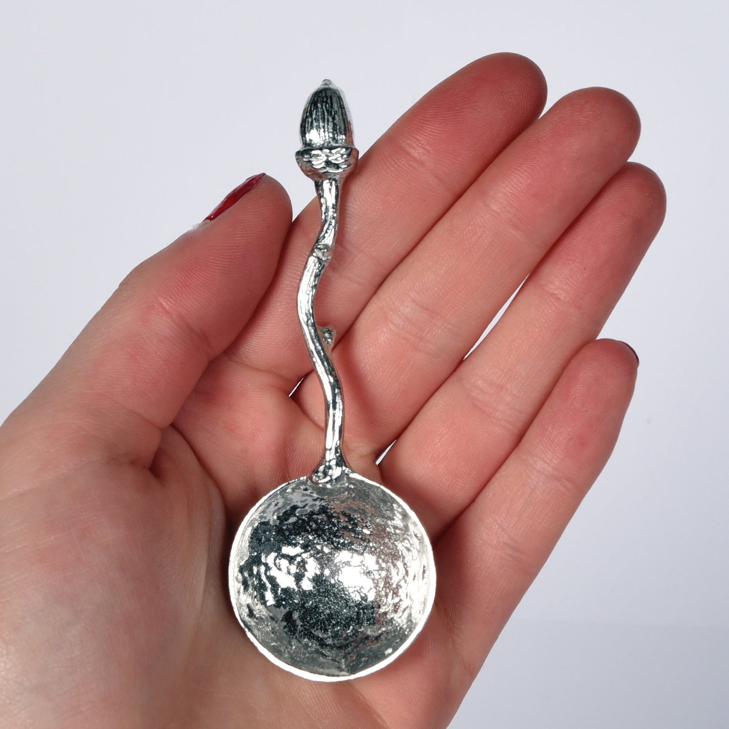 A small spoon pewter sugar spoon with an acorn on the end of a twig handle. Unusual, useful and tactile little acorn gifts handmade in the UK