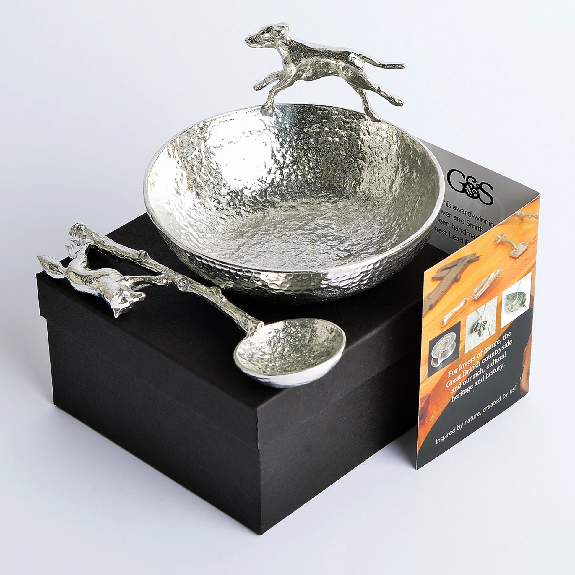 A magnificent hound bounds around the rim of a large textured, circular pewter bowl, chasing the accompanying spoon with a cunning fox on the end of its handle. Perfect gifts for lovers of the great British countryside. Country gifts, hunting gifts.