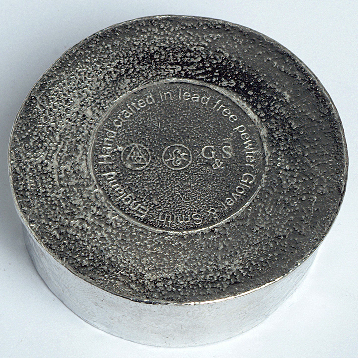 The underside of a Glover and Smith pewter box showing their makers marks