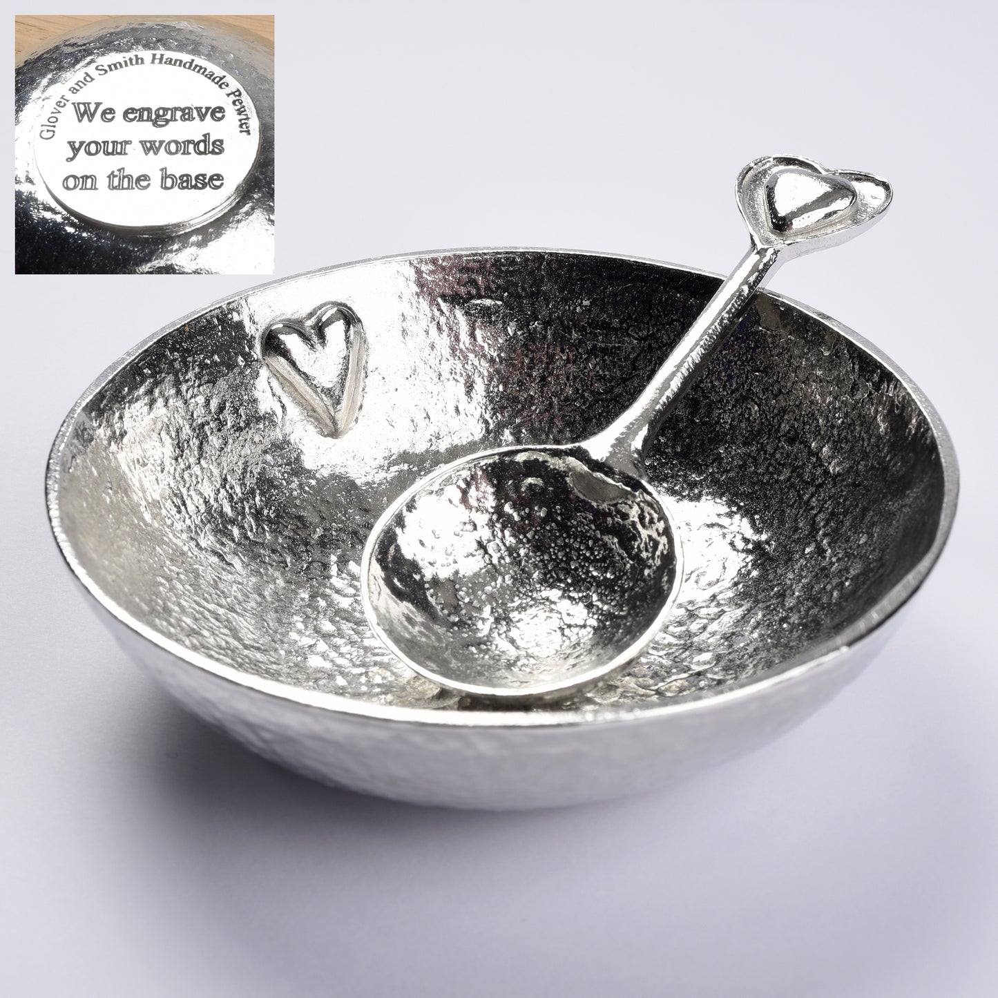 A textured pewter bowl with a raised small heart on the inner surface. It comes with a spoon with 2 hearts on the finial. One heart is within the other providing a tactile handle. The bowl of the spoon is round echoing the shape of the bowl. We engrave the base with your words.