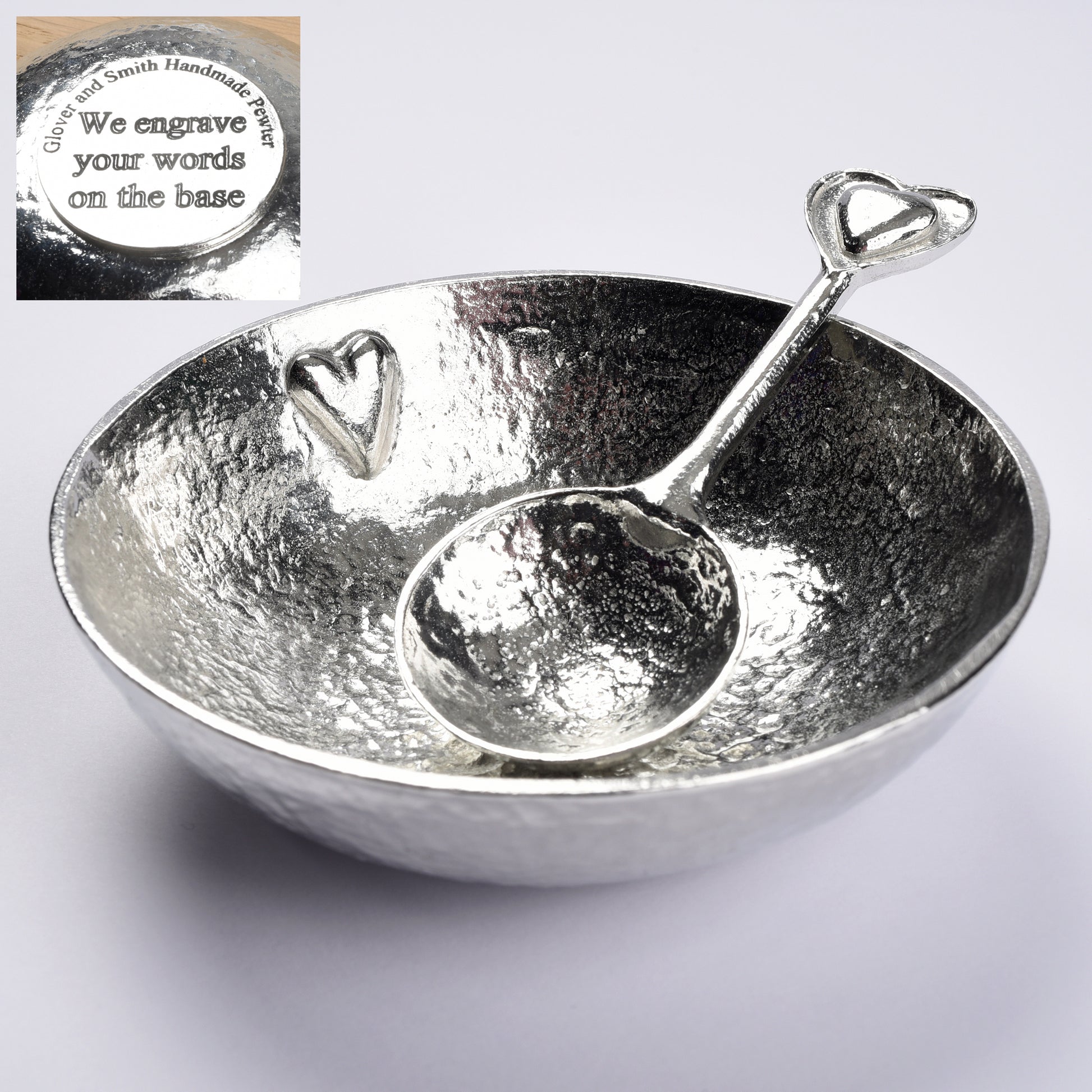 A textured pewter bowl with a raised small heart on the inner surface. It comes with a spoon with 2 hearts on the finial. One heart is within the other providing a tactile handle. The bowl of the spoon is round echoing the shape of the bowl. We engrave the base with your words.