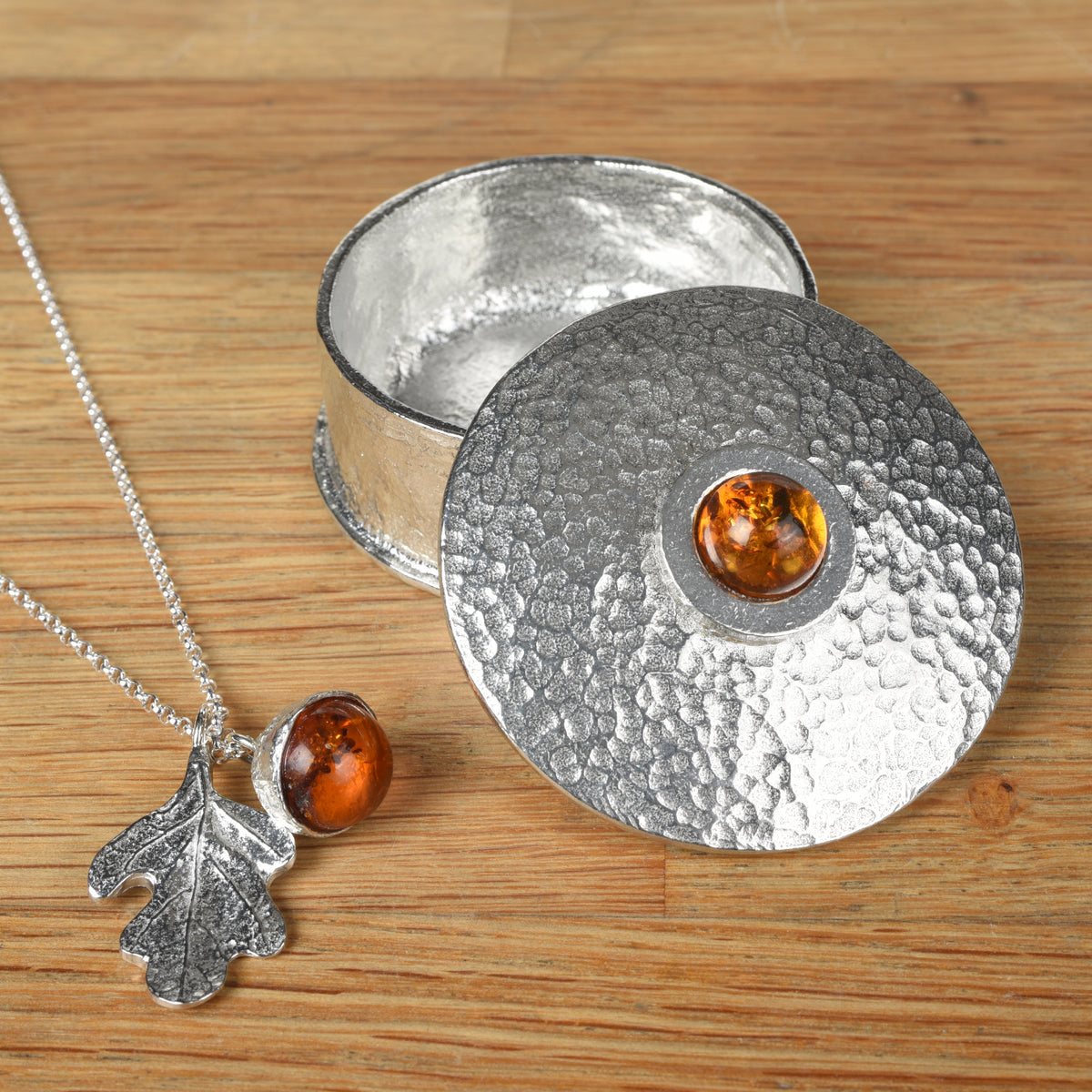 Amber acorn necklace pictured with a personalised, engraved amber birthstone box