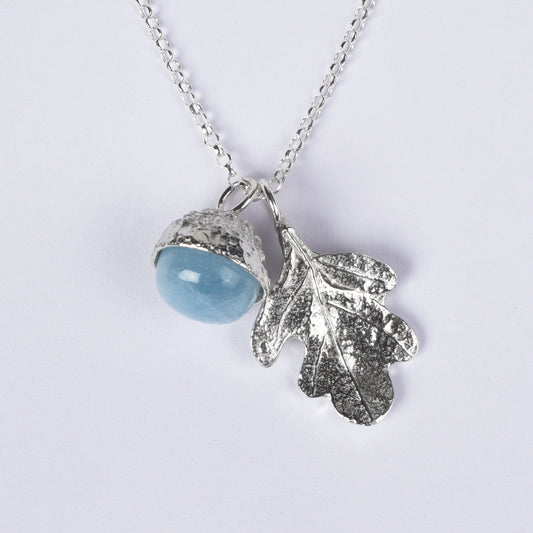 Pewter jewellery, an oak leaf necklace with an acorn cup with an aquamarine stone in it, March birthstone jewellery on a Sterling silver chain, white background