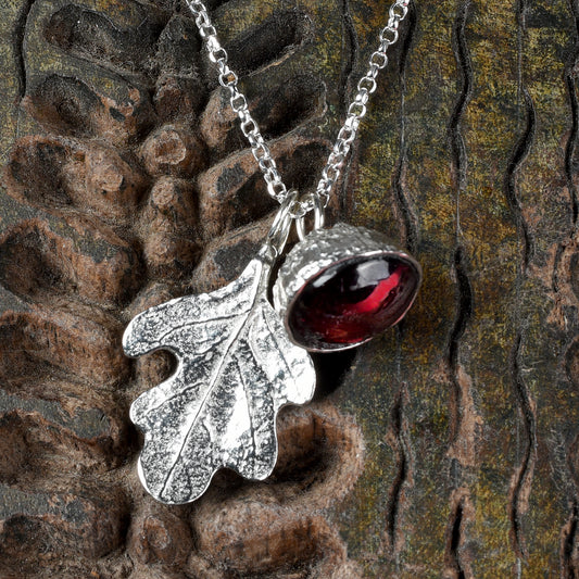 garnet acorn and oak leaf necklace on a textured wooden background