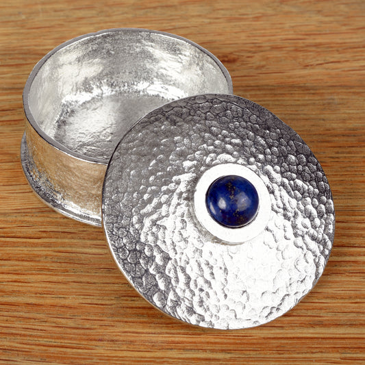 A round pewter box with a lapis lazuli deep blue stone in the centre of the lid, made by Glover and Smith