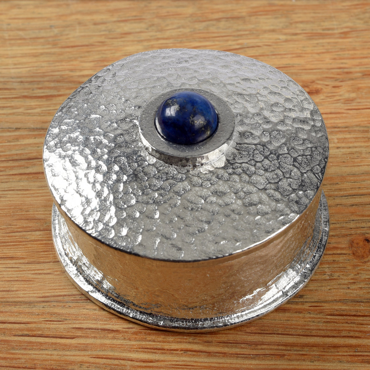 A round pewter box with a lapis lazuli deep blue stone in the centre of the lid, made by Glover and Smith