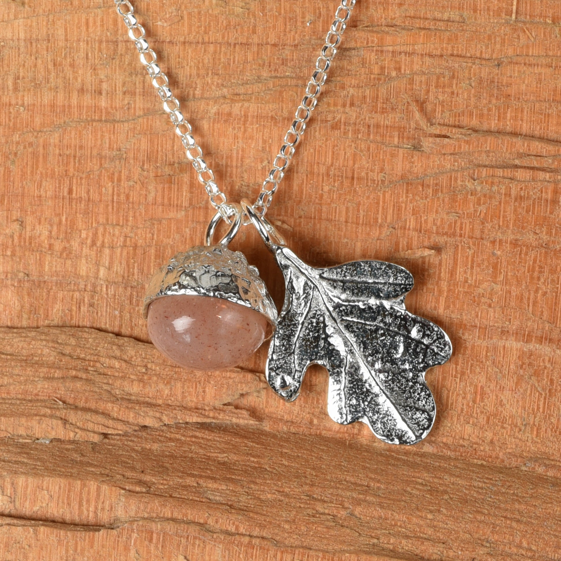 moonstone in a pewter acorn cup with an oak leaf on a Sterling silver necklace. Textured wood background