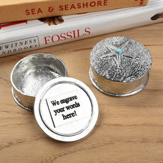 A round  pewter trinket box with a starfish on the lid. A turquoise stone sits on the meeting point of the 5 legs. Nautical gifts for lovers of the seaside and sea life. We engrave the lid with your personalised message.