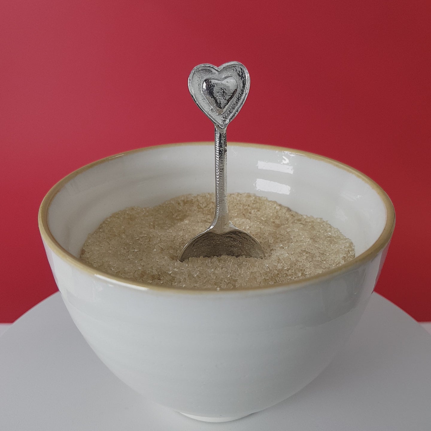 Video of a handmade pewter spoon with a heart on the handle. The spoon is in a revolving sugar bowl.