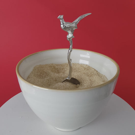 Video of a handmade pewter spoon with a pheasant on the handle. The spoon is in a revolving sugar bowl.