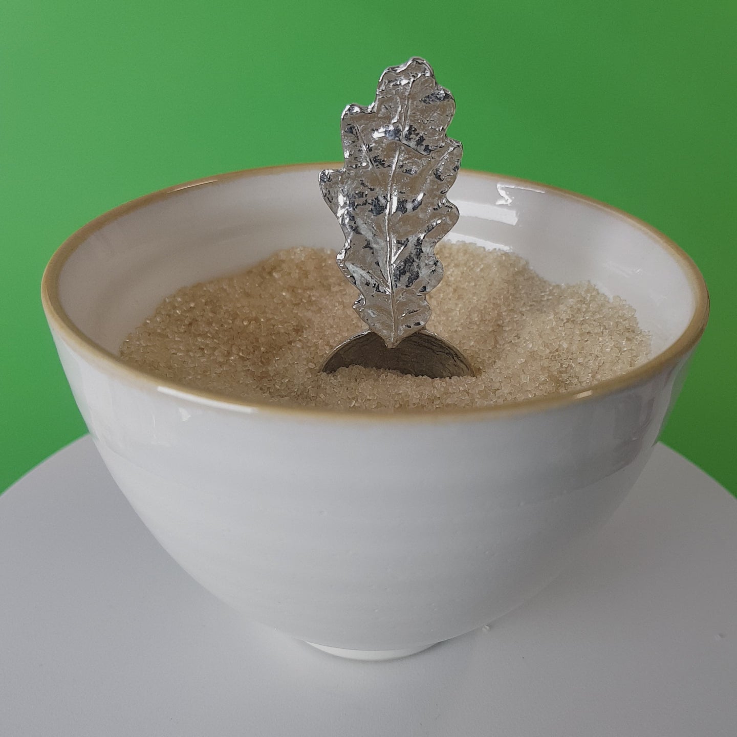 Video of a handmade pewter spoon with an oak leaf handle. The spoon is in a revolving sugar bowl.