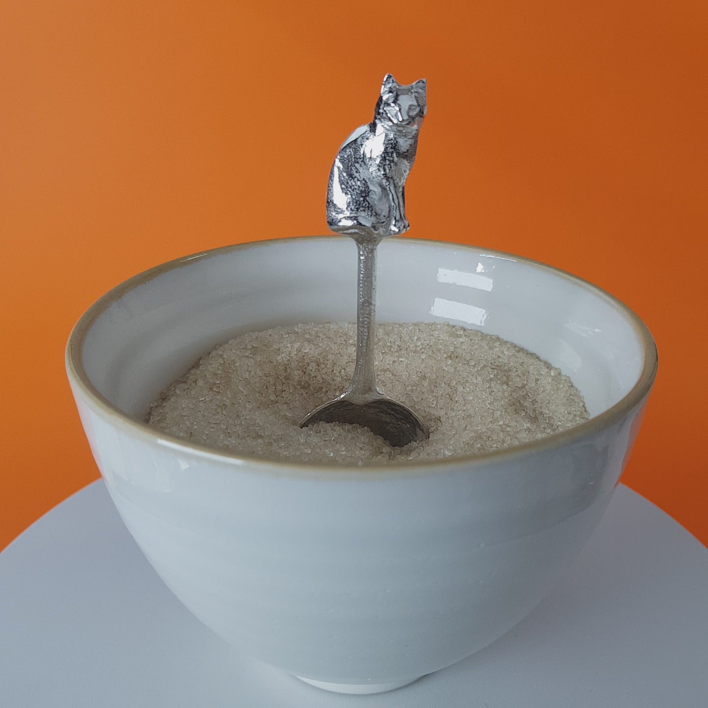 Video of a handmade pewter spoon with a cat on the handle. The spoon is in a revolving sugar bowl.