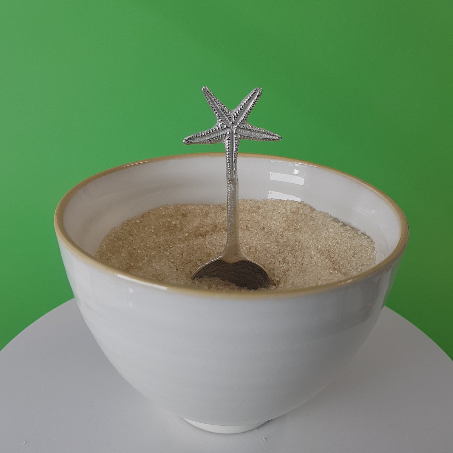 Video of a handmade pewter spoon with a starfish on the handle. The spoon is in a revolving sugar bowl.