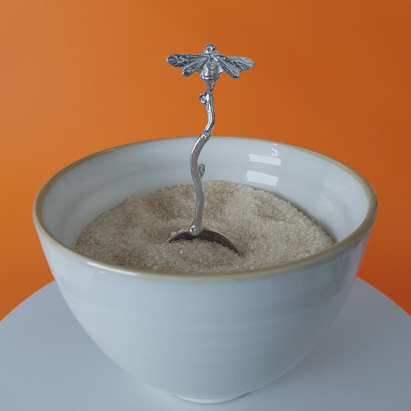 Video of a handmade pewter spoon with a bee on the handle. The spoon is in a revolving sugar bowl.