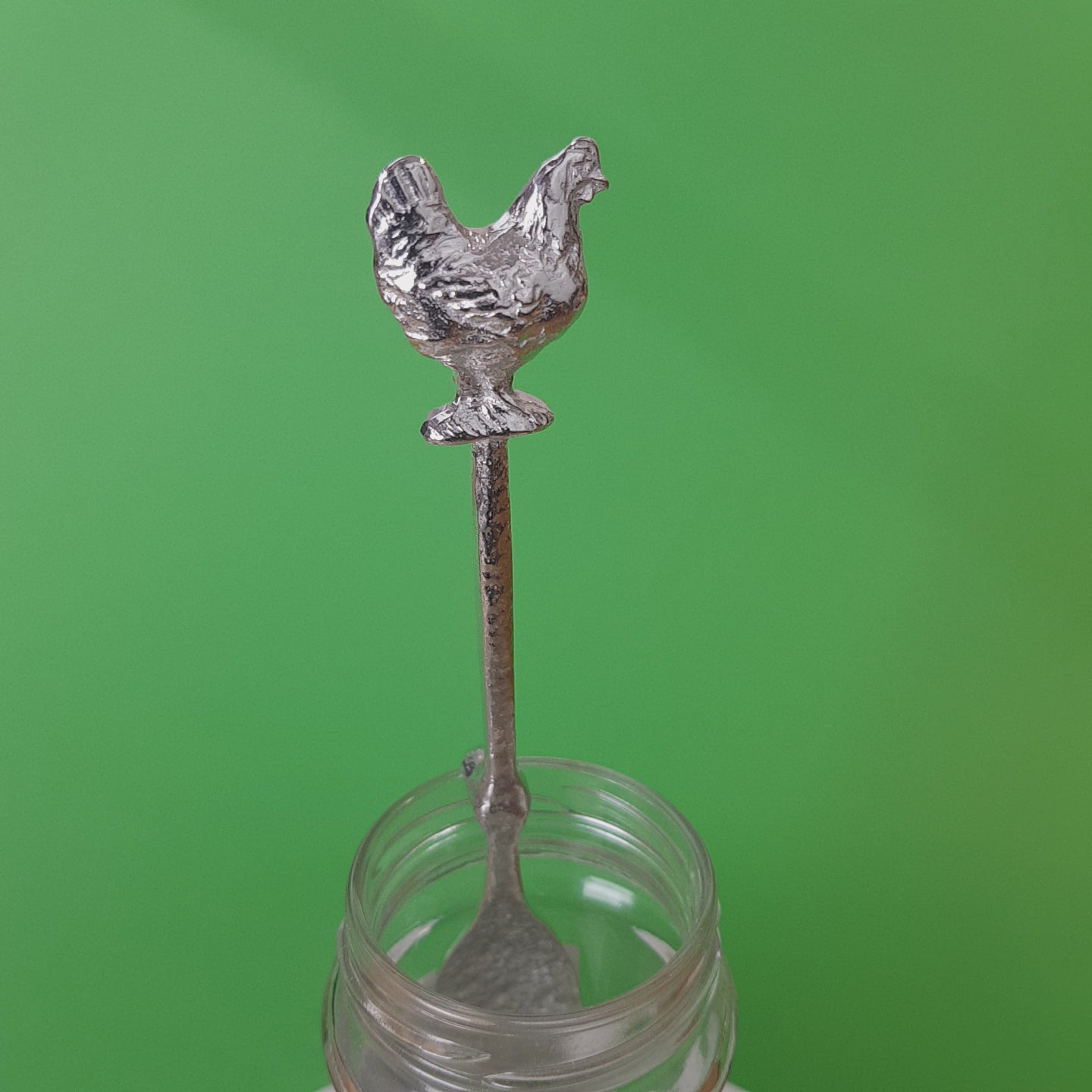 Long pewter jam spoon with a hook to hang on any jar. The top of the spoon has a chicken sculpture on it.