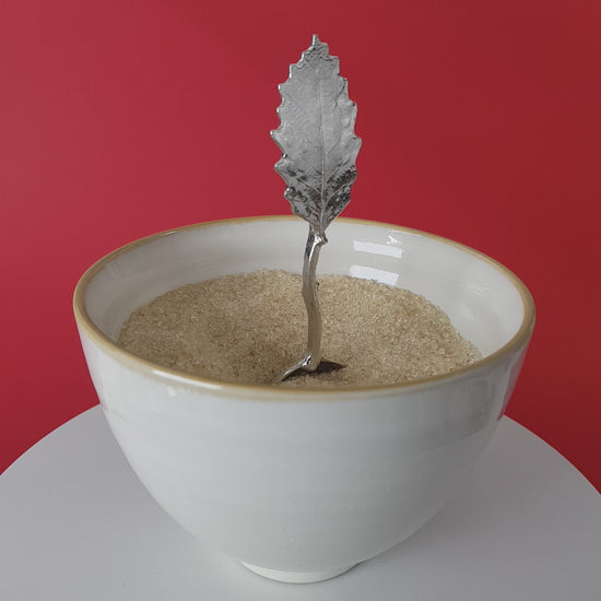 Video of a handmade pewter spoon with a chestnut leaf handle. The spoon is in a revolving sugar bowl.