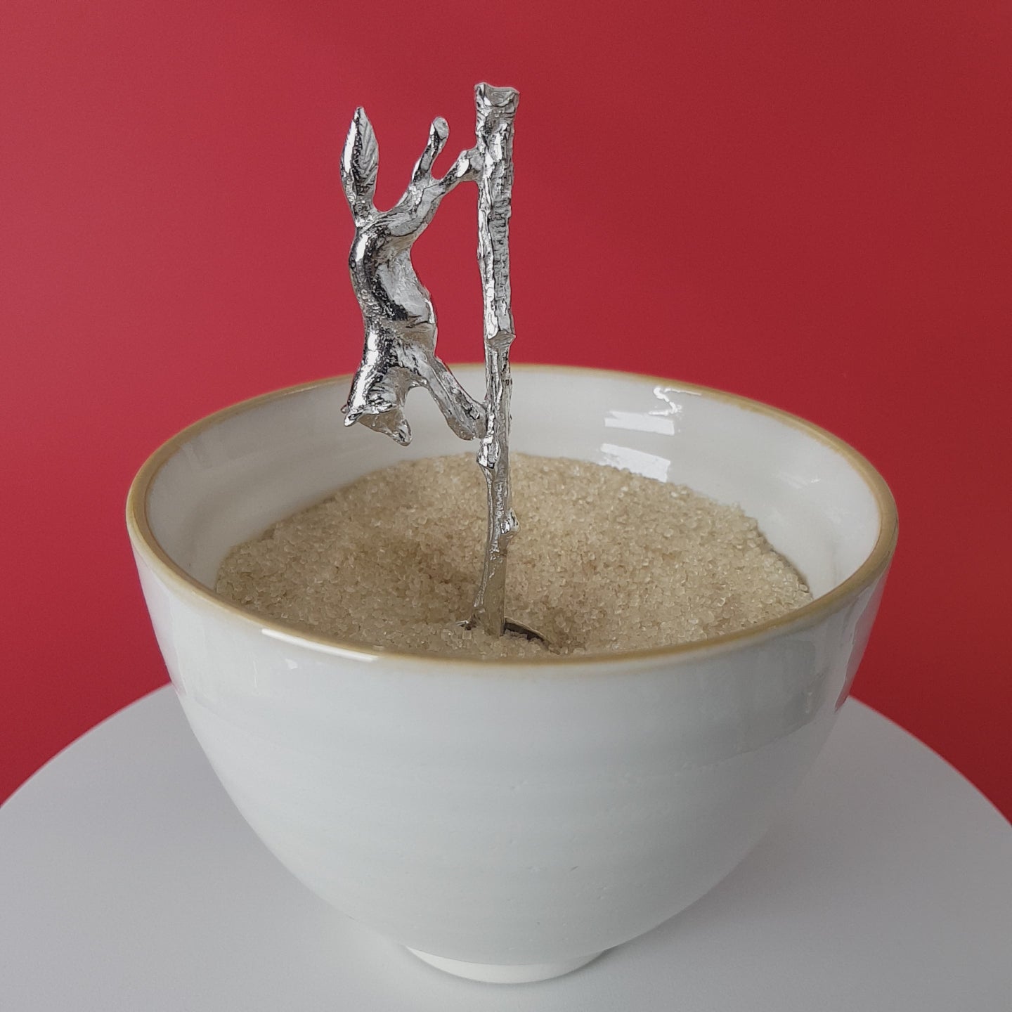 Video of a handmade pewter spoon with a running fox handle. The spoon is in a revolving sugar bowl.