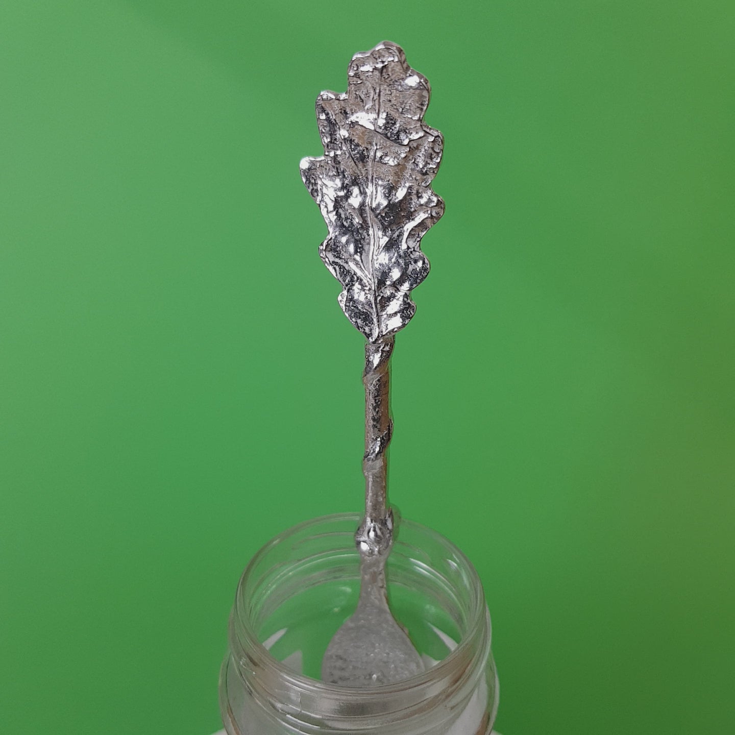 Long pewter jam spoon with a hook to hang on any jar. The top of the spoon has an oak leaf sculpture on it.
