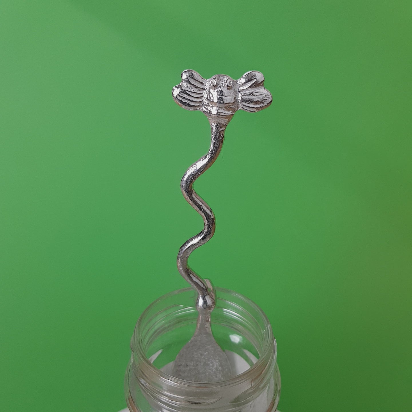 Long pewter jam spoon with a hook to hang on any jar. The top of the spoon has a bee sculpture on it.