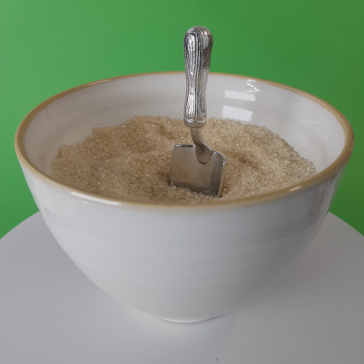 Video of a handmade pewter spoon in the shape of a garden trowel. The spoon is in a revolving sugar bowl.