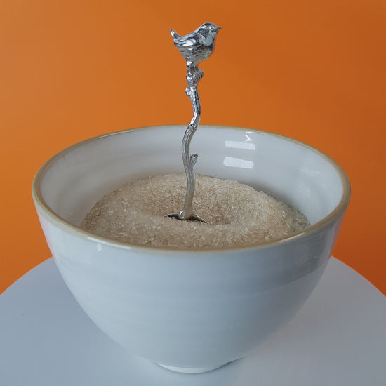 Video of a handmade pewter spoon with a wren sculpture on the handle. The spoon is in a revolving sugar bowl.