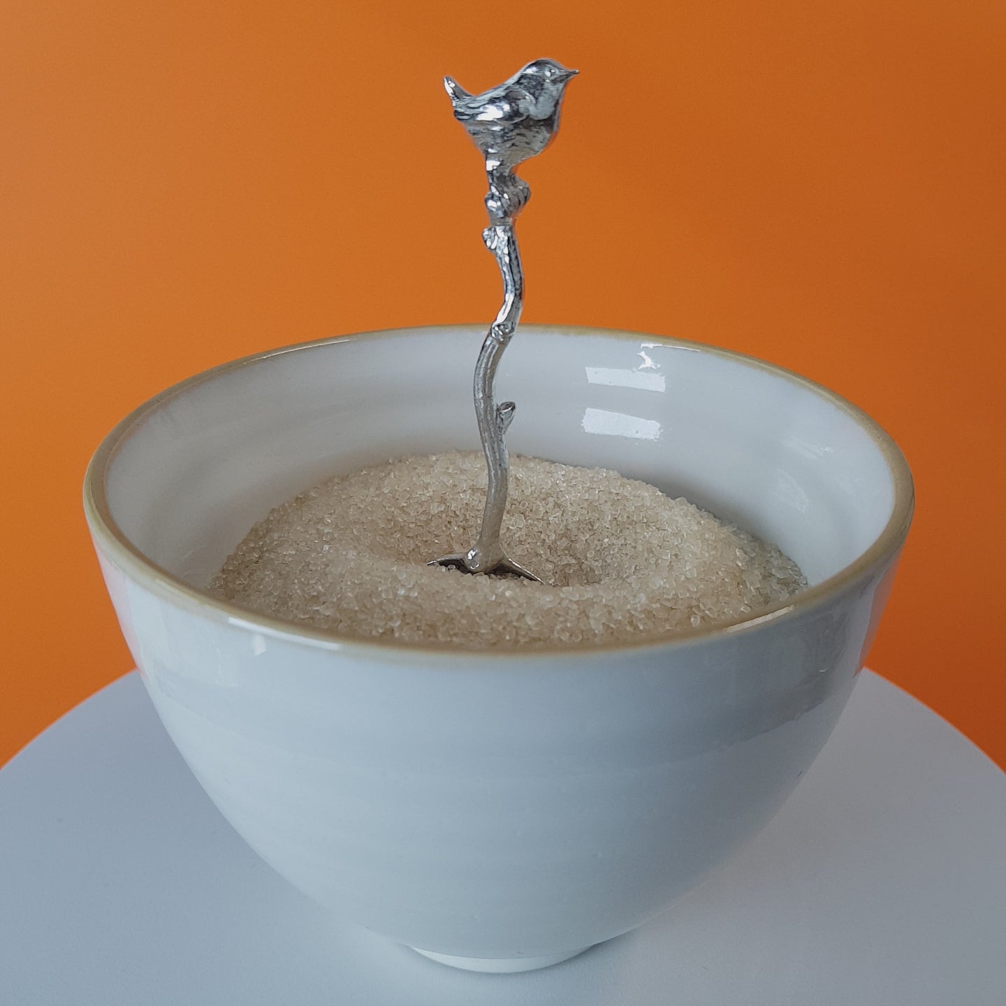 Video of a handmade pewter spoon with a wren sculpture on the handle. The spoon is in a revolving sugar bowl.