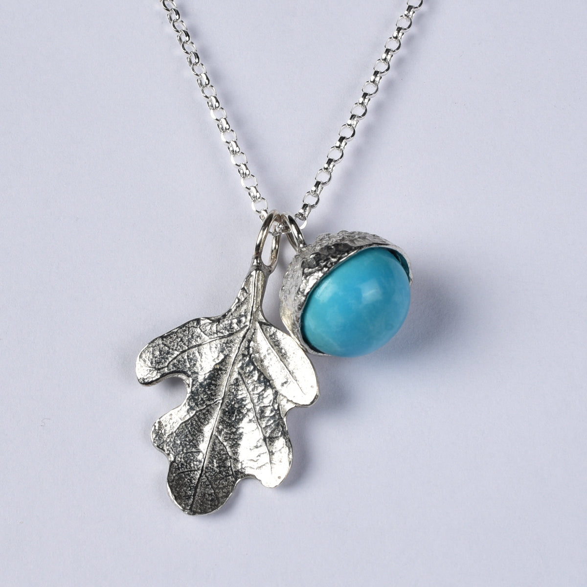 A  turquoise acorn and oak leaf pewter necklace. December birthstone gifts shown against a white background
