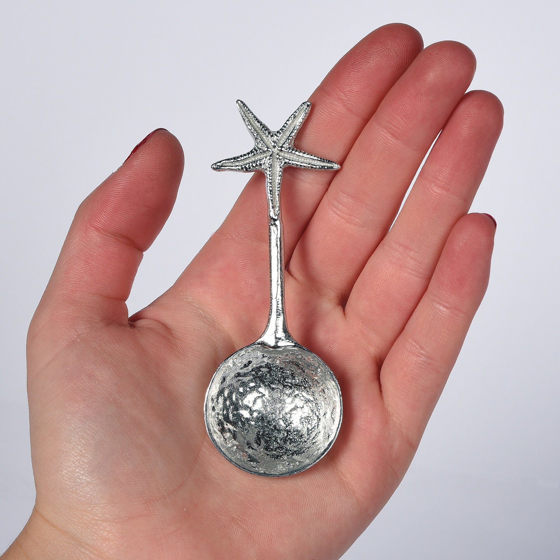 A small spoon pewter sugar spoon. A round bowled spoon on a straight handle leads to a perfectly sculpted starfish. Practical & useful nautical gifts for starfish lovers. UK handmade