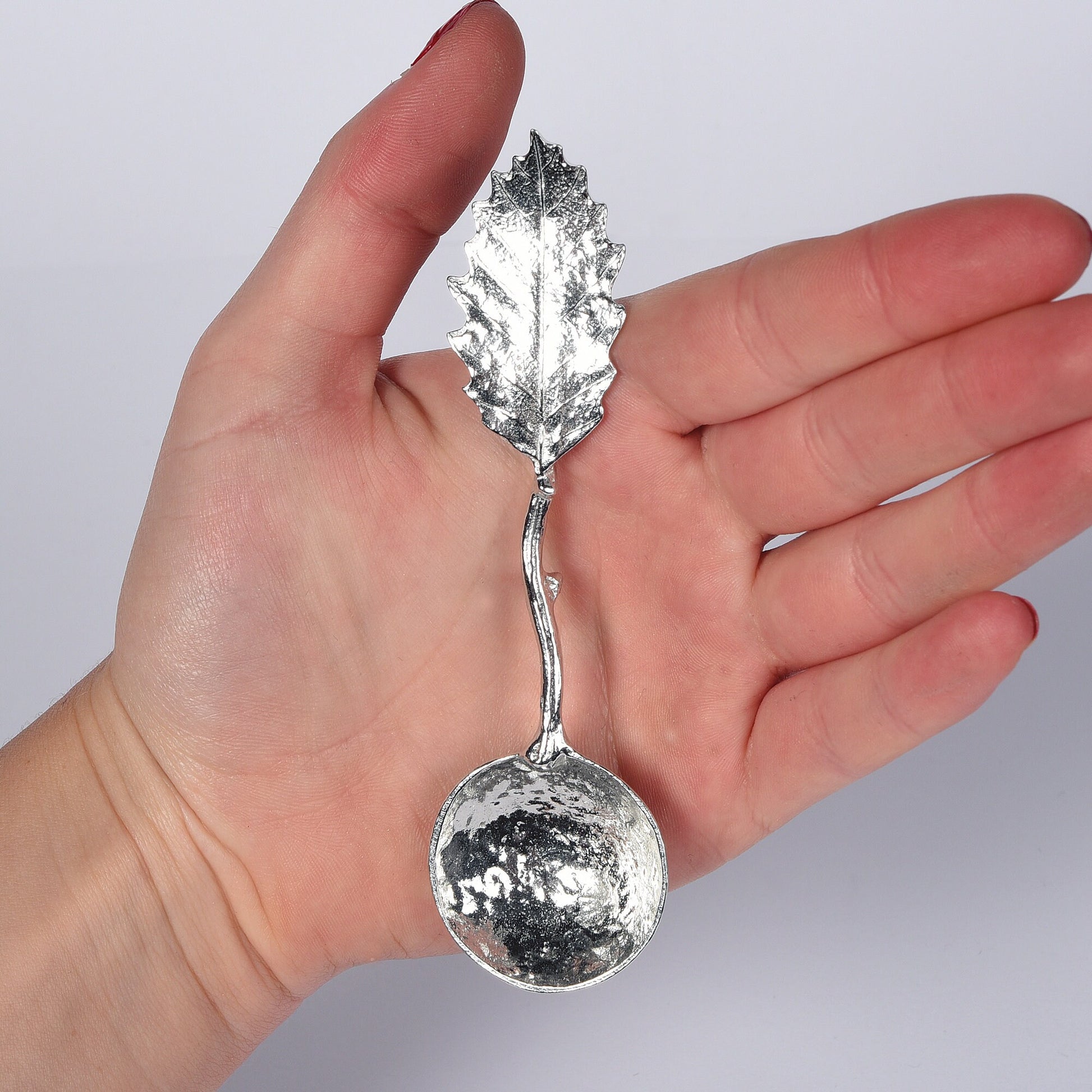 A small spoon pewter sugar spoon with a detailed chestnut leaf on the end of a twig handle. Unusual, useful and tactile gifts for nature lovers handmade in the UK