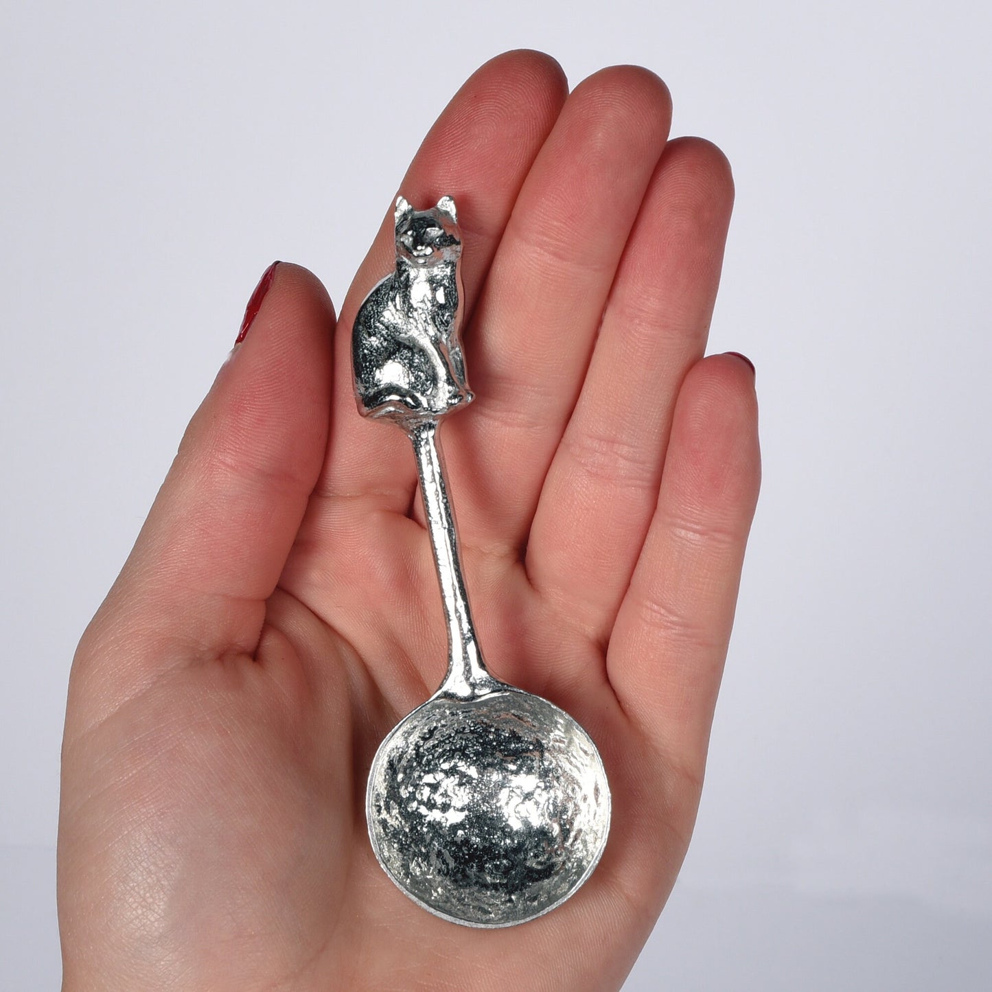 A small spoon pewter sugar spoon. A round bowled spoon on a straight handle leads to a perfectly sculpted cat. Practical & useful cat gifts for cat lovers. UK handmade