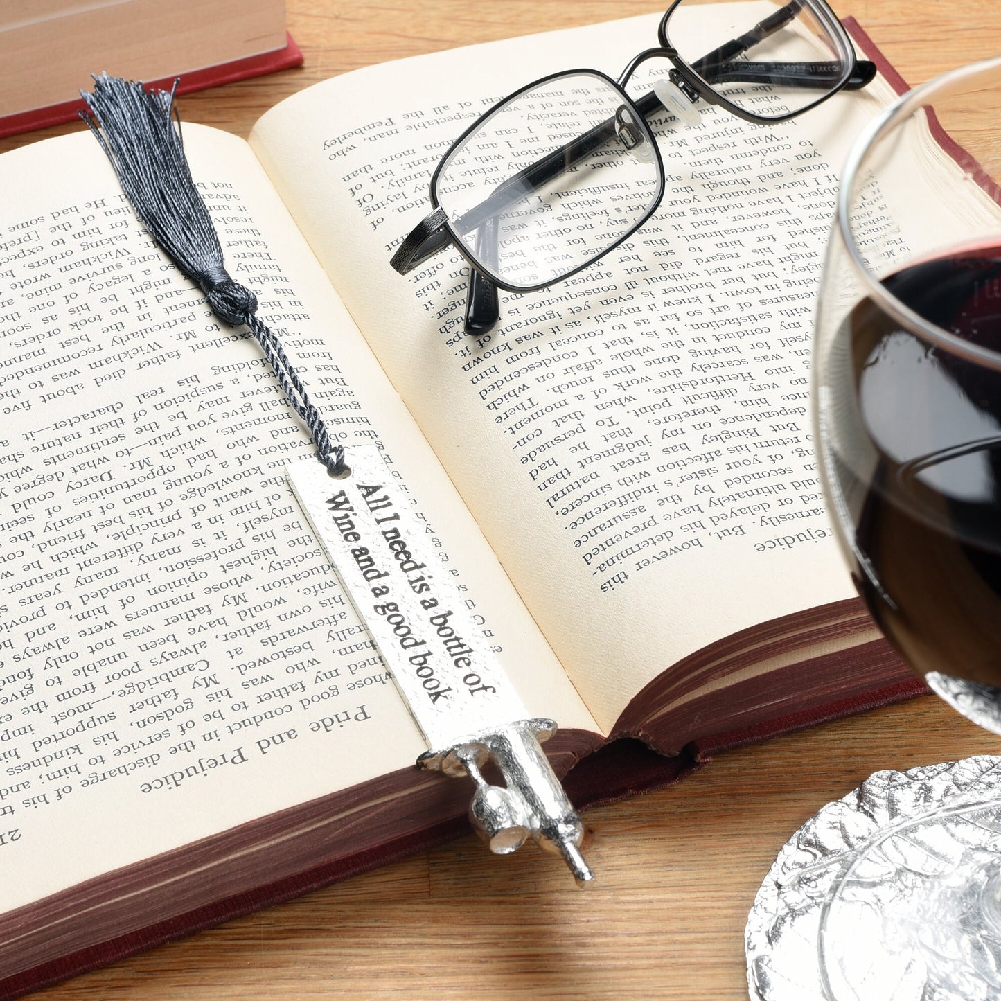 A personalised engraved pewter metal  bookmark with a wine bottle and glass on the top. On the front the quotation 'All I need is a bottle of wine and a good book'. We engrave the back with your message. Gifts for wine lovers, book lovers gifts.