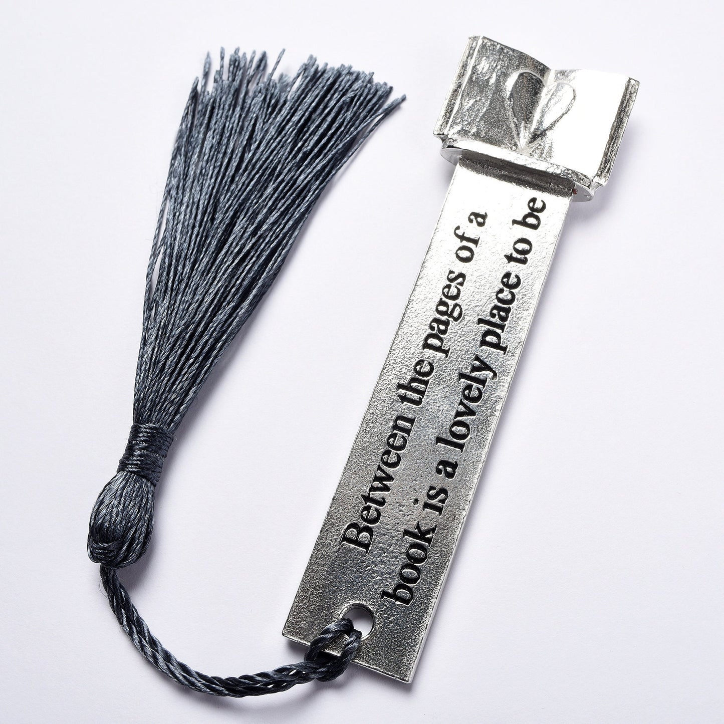 A personalised engraved pewter metal  bookmark with a heart on an open book on the top. On the front the quotation 'Between the pages of a book is a lovely place to be'. Gifts for book lovers, book gifts, bookmarks for books