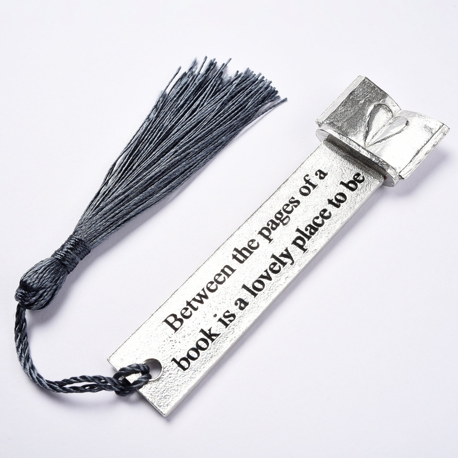 A personalised engraved pewter metal  bookmark with a heart on an open book on the top. On the front the quotation 'Between the pages of a book is a lovely place to be'. Gifts for book lovers, book gifts, bookmarks for books