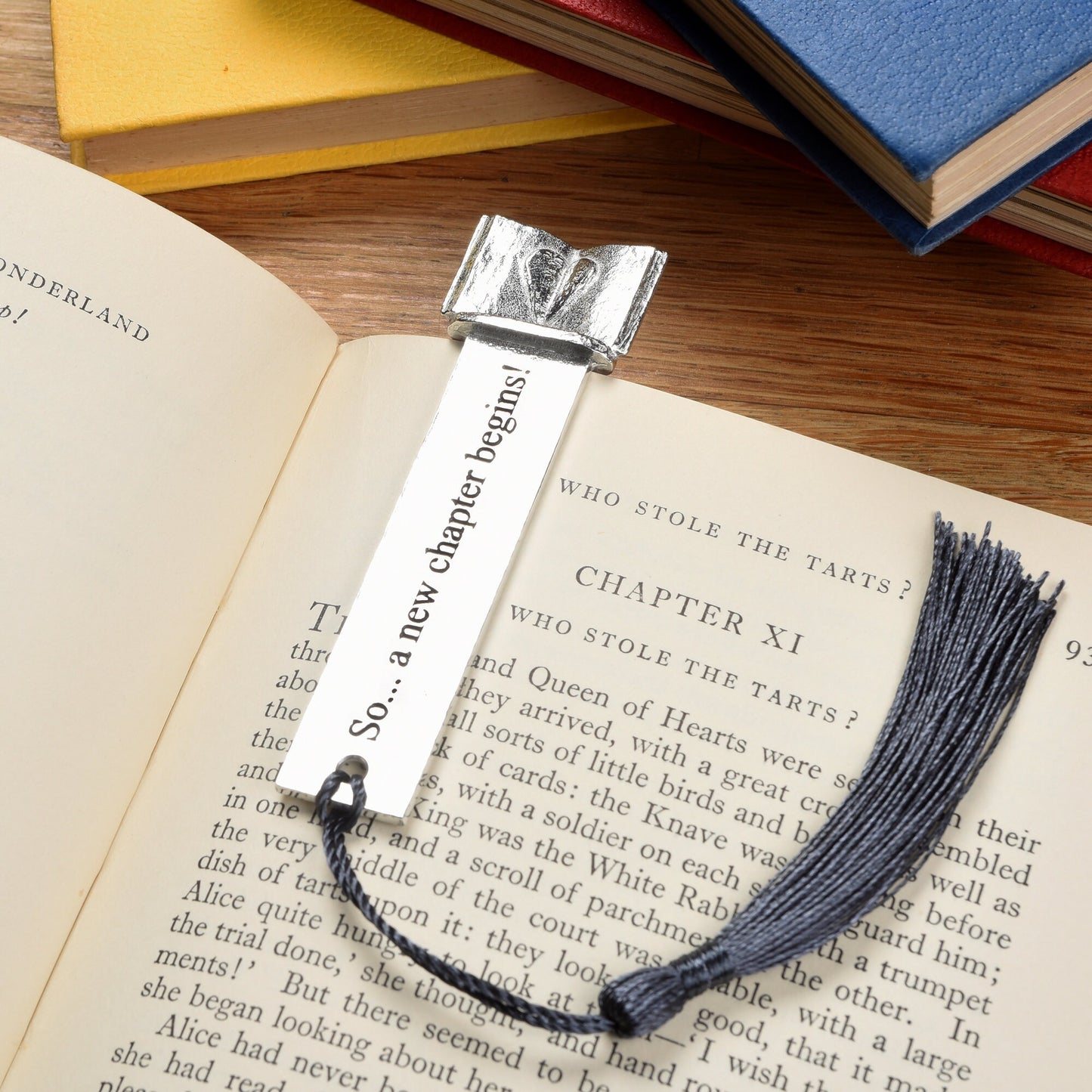 A personalised engraved pewter metal  bookmark with a heart on an open book on the top. On the front the quotation 'So... a new chapter begins'. New chapter gifts, personalised gifts, new job gifts. We engrave the back with your message