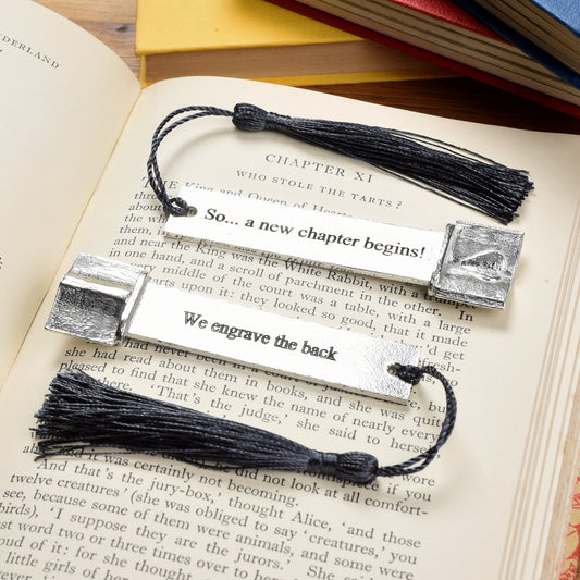 A personalised engraved pewter metal  bookmark with a heart on an open book on the top. On the front the quotation 'So... a new chapter begins'. New chapter gifts, personalised gifts, new job gifts. We engrave the back with your message