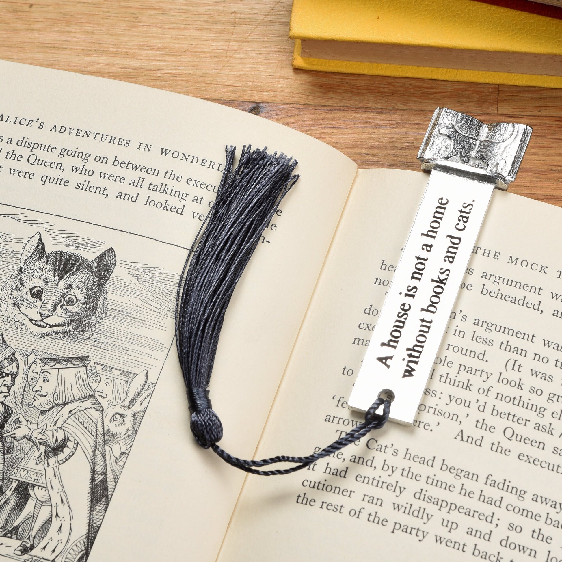 A  pewter metal  bookmark with a cat silhouette wandering across an open book on the top. On the front the quotation 'A house is not a home without books and cats'. Gifts for cat lovers, book lovers gifts, cat gifts.