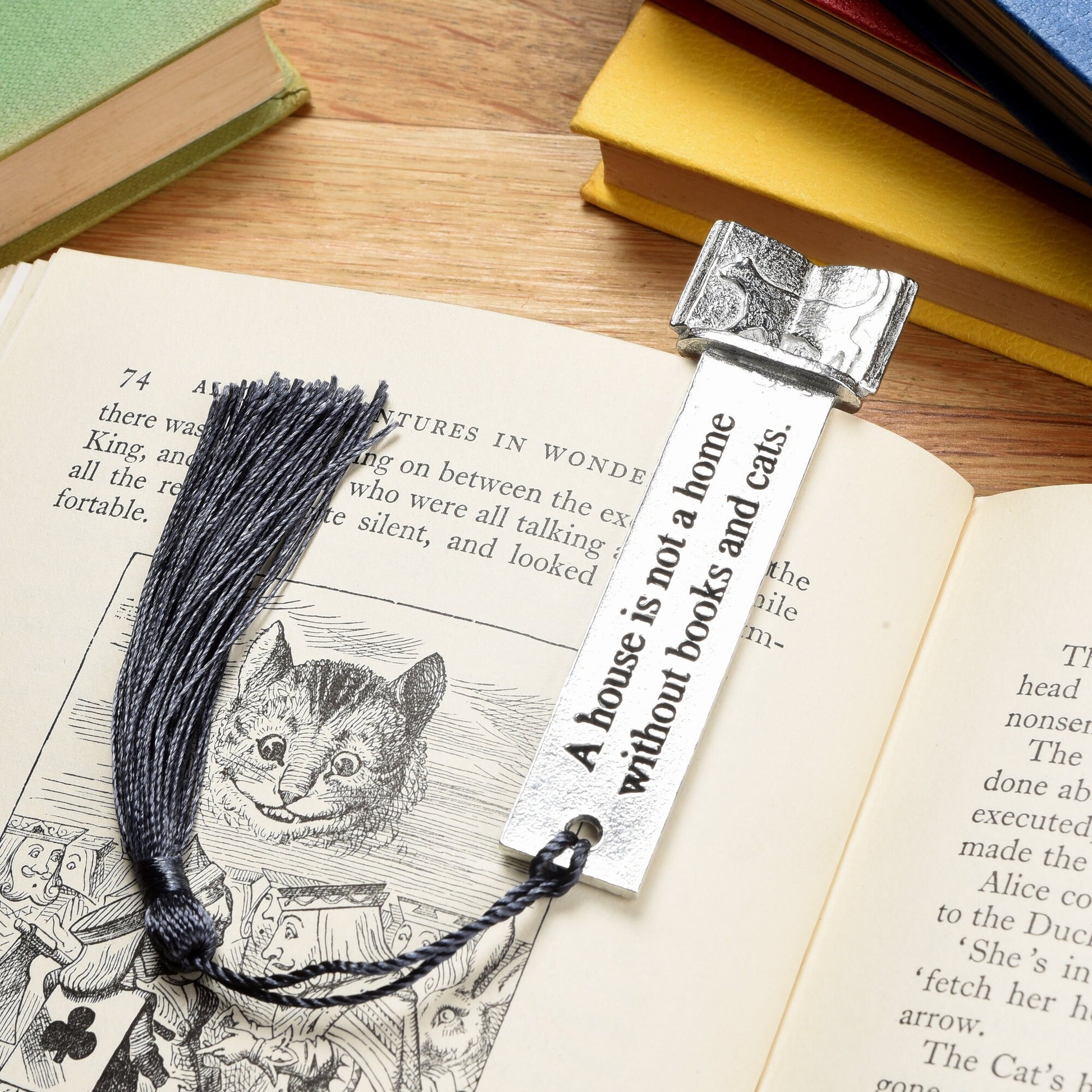 A  pewter metal  bookmark with a cat silhouette wandering across an open book on the top. On the front the quotation 'A house is not a home without books and cats'. Gifts for cat lovers, book lovers gifts, cat gifts.