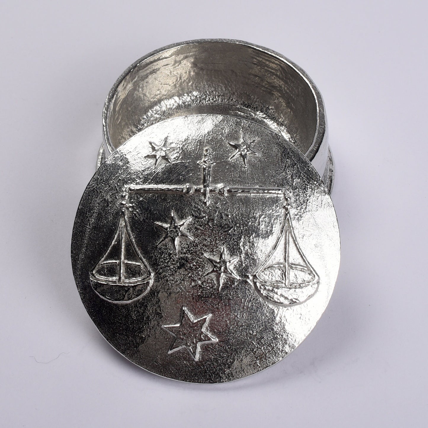 A beautifully detailed and textured Libra scales zodiac sign guards precious treasure on this personalised pewter trinket box. The underside of the lid can be engraved with your personalised message. Birthday gifts for Libras - made in Britain.