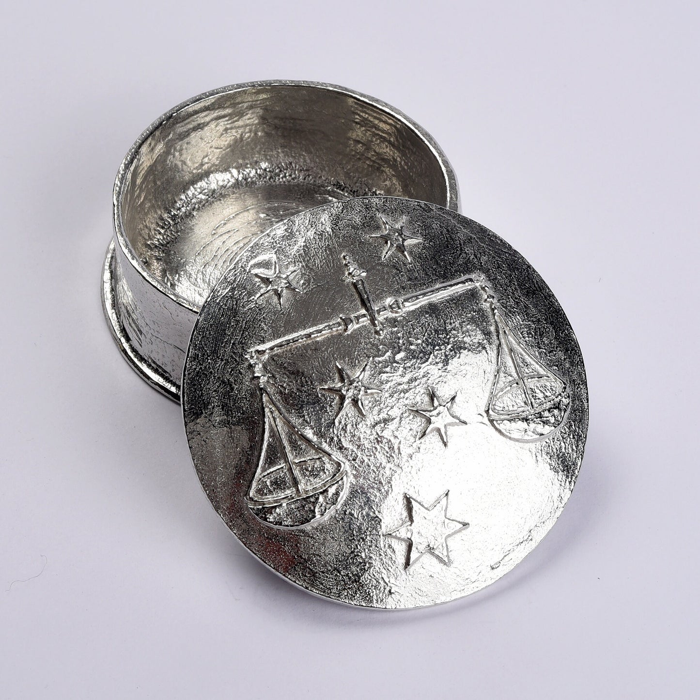 A beautifully detailed and textured Libra scales zodiac sign guards precious treasure on this personalised pewter trinket box. The underside of the lid can be engraved with your personalised message. Birthday gifts for Libras - made in Britain.