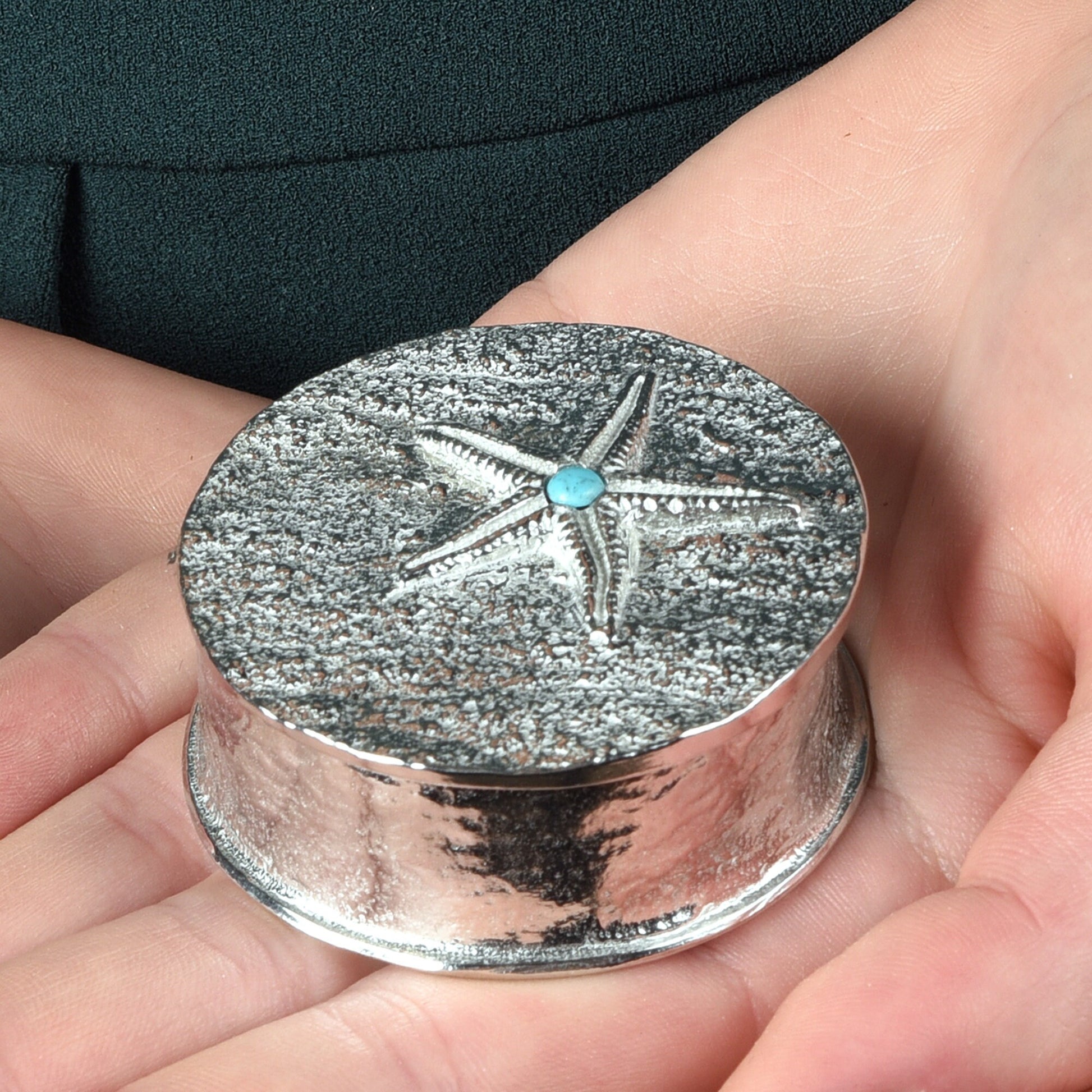 A round  pewter trinket box with a starfish on the lid. A turquoise stone sits on the meeting point of the 5 legs. Nautical gifts for lovers of the seaside and sea life.