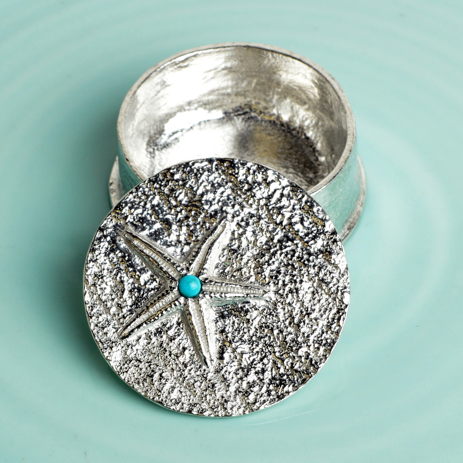 A round  pewter trinket box with a starfish on the lid. A turquoise stone sits on the meeting point of the 5 legs. Nautical gifts for lovers of the seaside and sea life.