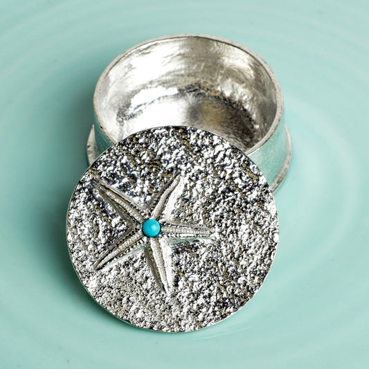 A round  pewter trinket box with a starfish on the lid. A turquoise stone sits on the meeting point of the 5 legs. Nautical gifts for lovers of the seaside and sea life.