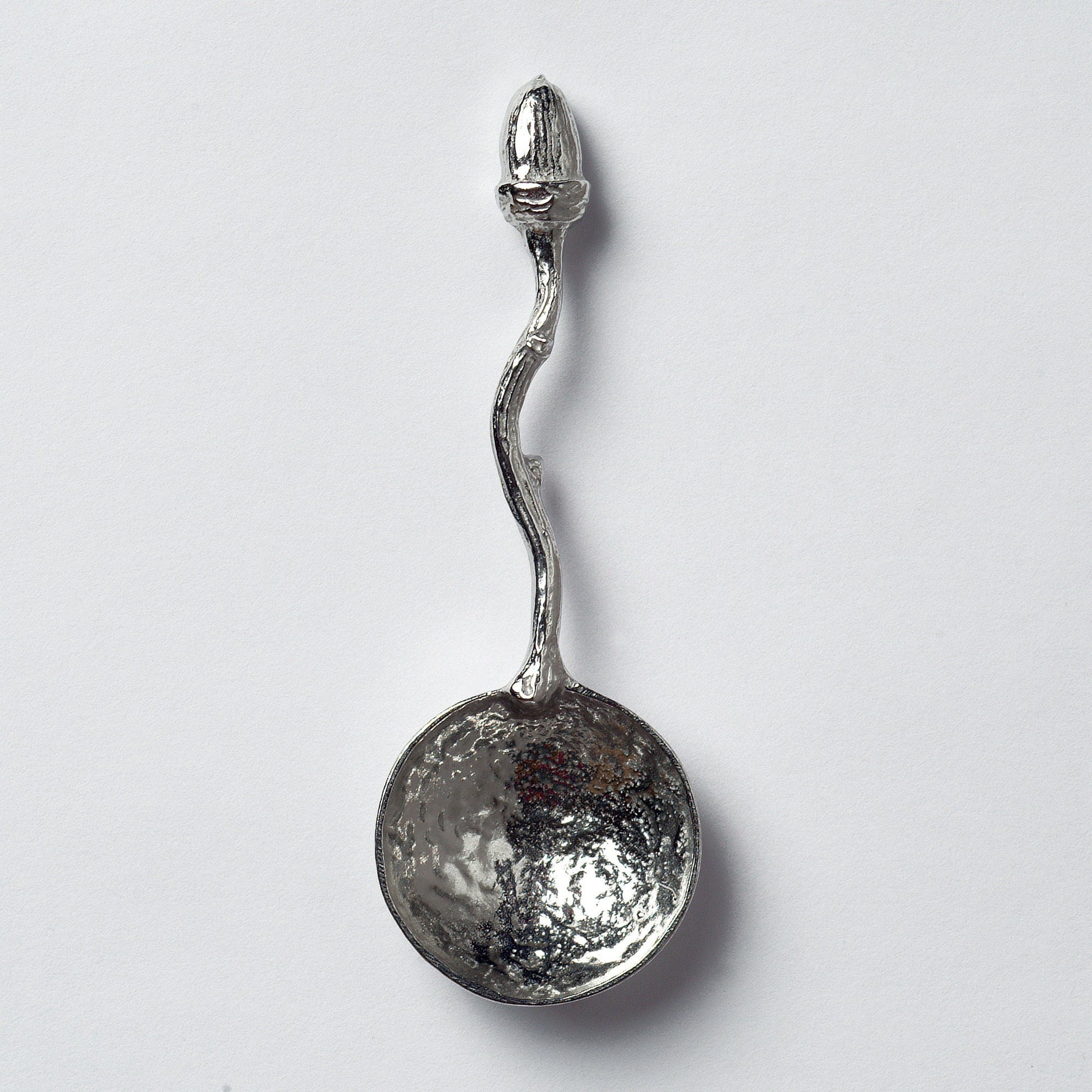 A small spoon pewter sugar spoon with an acorn on the end of a twig handle. Unusual, useful and tactile little acorn gifts  handmade in the UK