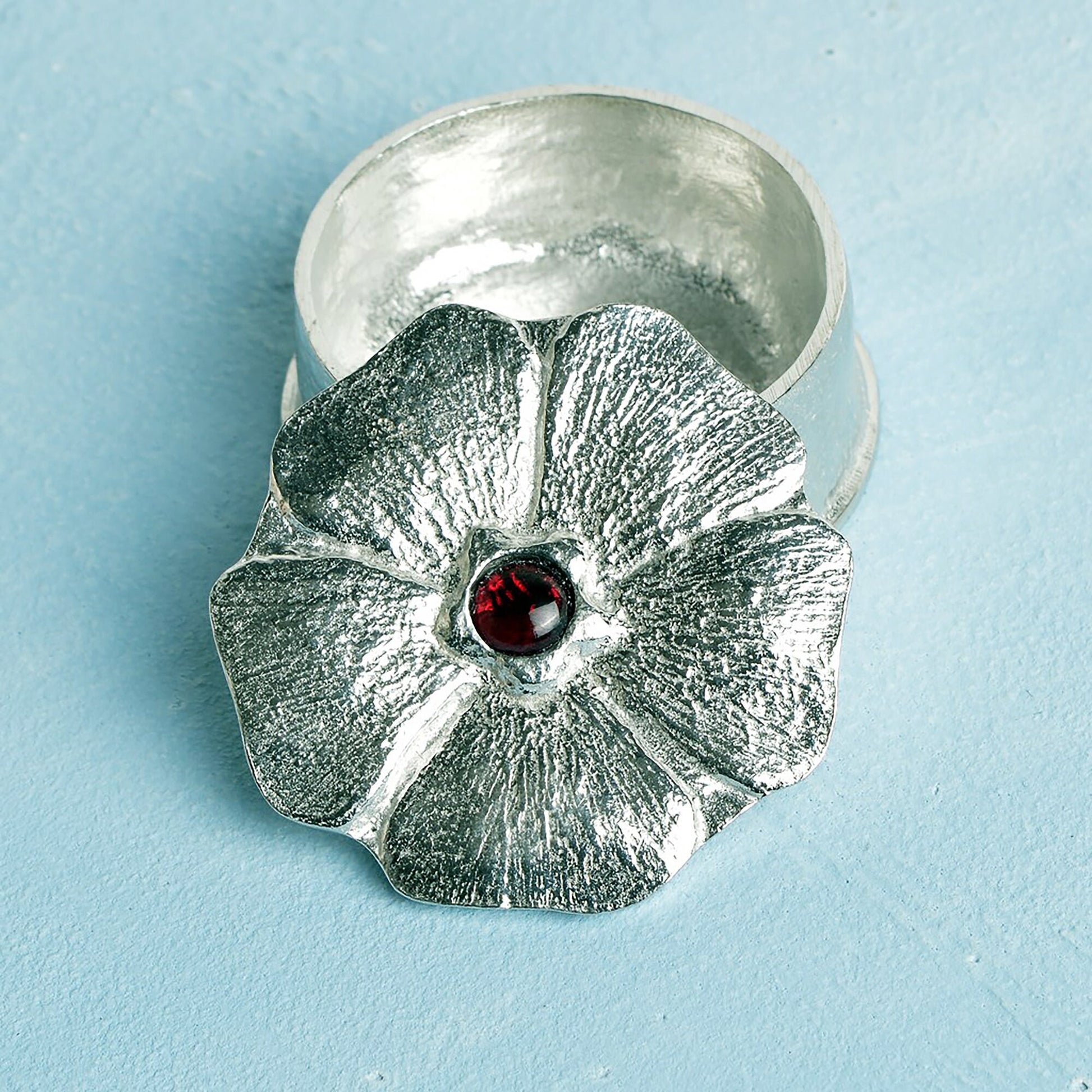 A forget me not flower pewter keepsake trinket box has a garnet stone in the middle. A perfect 10th (Tin) ten year wedding anniversary gift (Our pewter is 95% tin). Great gifts for bridesmaids or a small wedding gift.